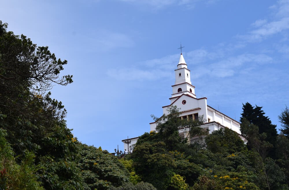Cerro Monserrate com muitas árvores e uma basílica branca no topo.