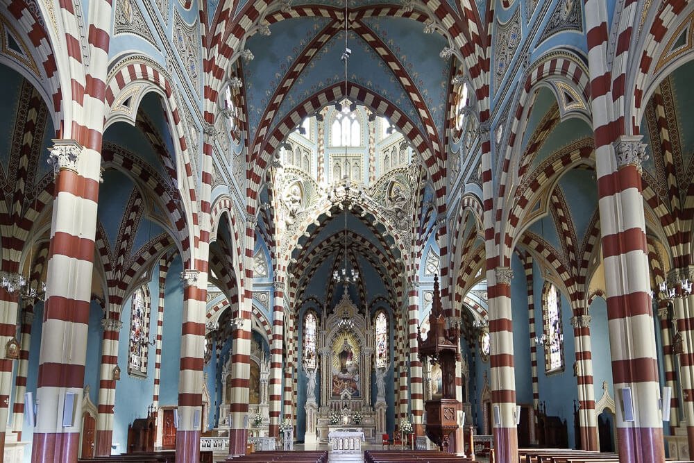 Santuario Nuestra Señora del Carmen visto por dentro com altar majestoso e decoração em listras brancas e vermelhas.