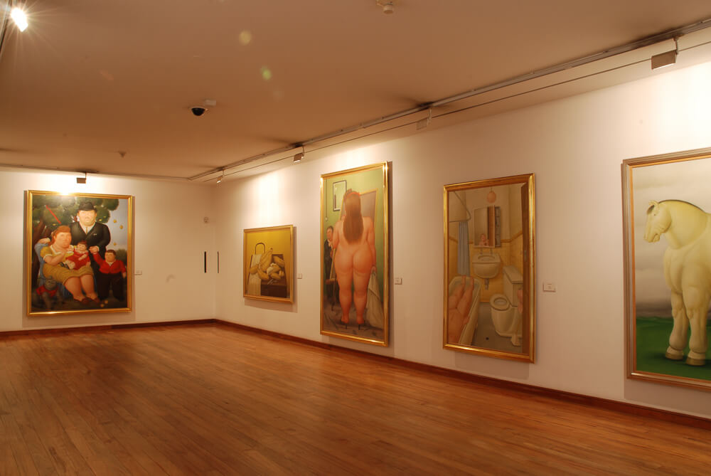 Sala no interior do Museo Botero com várias pinturas expostas nas paredes.