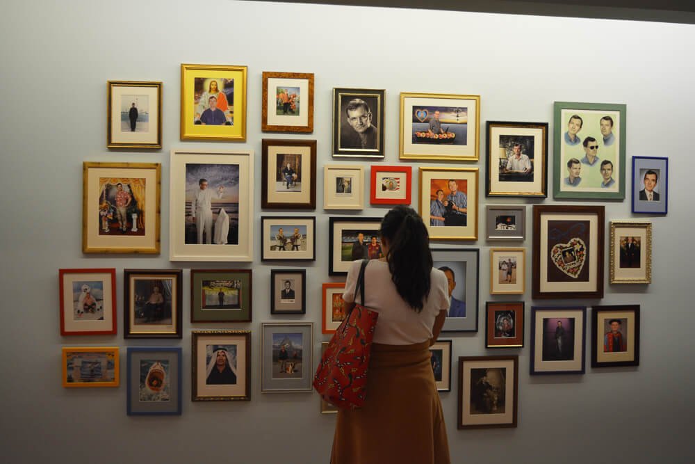Mulher de costas contemplando vários quadros expostos no Museu de Arte Miguel Urrutia.