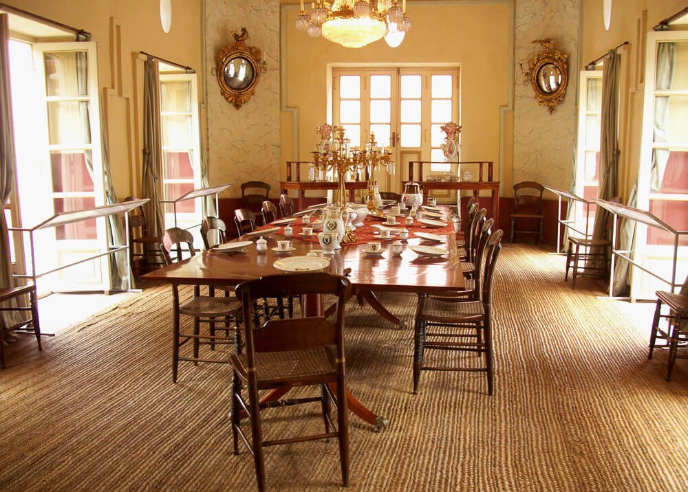 Interior aconchegante do Museo Quinta de Bolívar com mesa grande e rodeada de cadeiras.