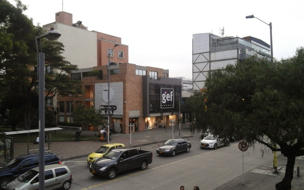 Rua na Zona Rosa com árvores, carros e prédios comerciais modernos.
