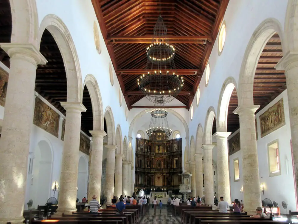 Interior da Catedral de Santa Catalina de Alejandría. Há vários bancos de madeira e vários fiéis em pé.