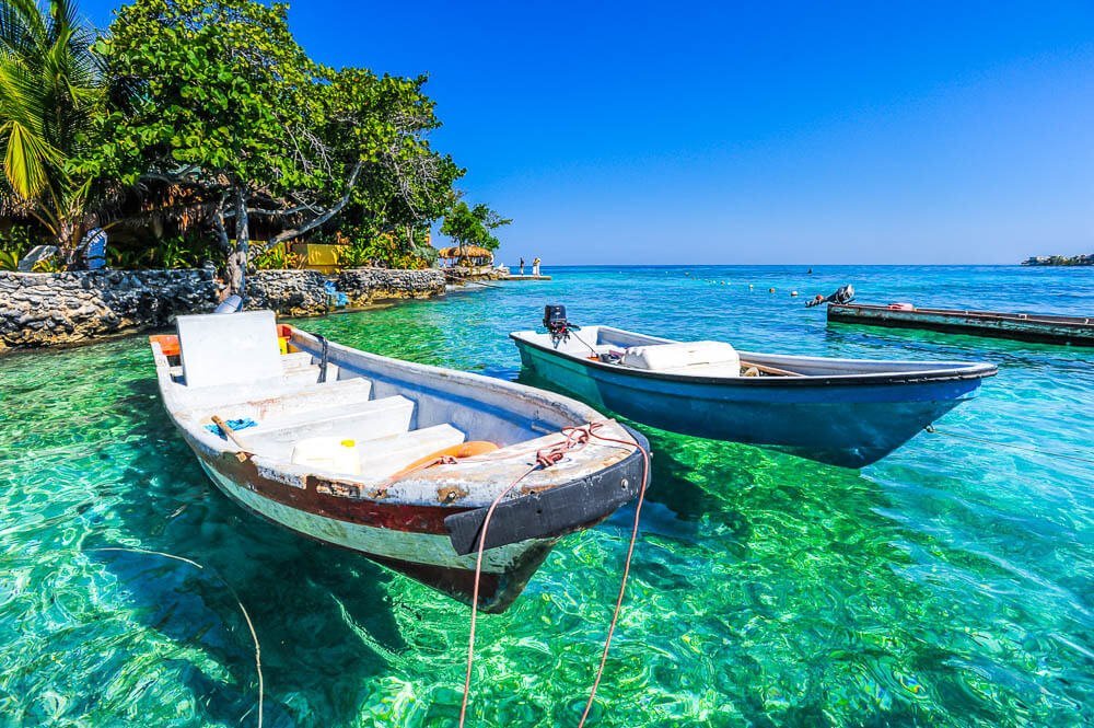 Três pequenos barcos sobre as águas azuis-turquesa da Isla del Rosario.