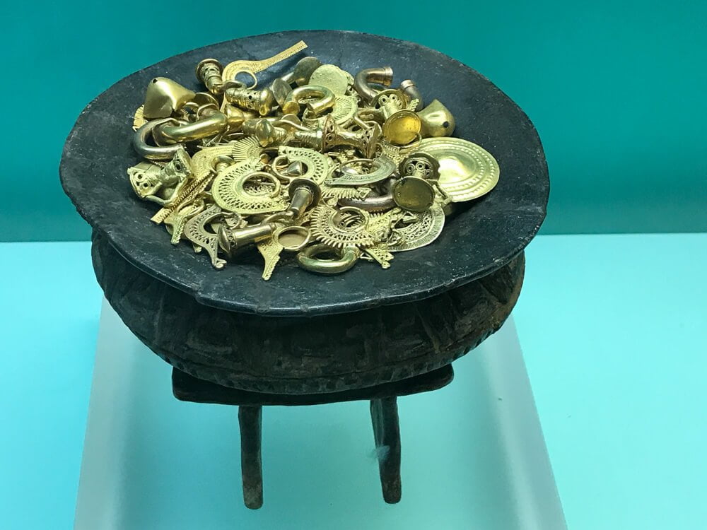 Peças de ouro sobre um pequeno suporte preto.