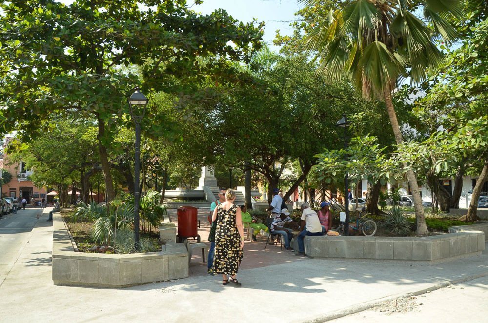 Plaza Fernandez Madrid em um dia de sol. Há várias árvores e algumas pessoas na praça.