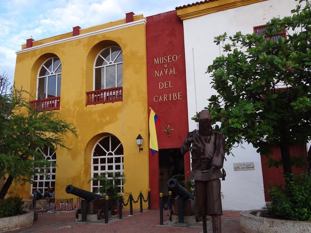 Entrada do Museu Naval do Caribe. Há canhões próximo à porta e a bandeira da Colômbia hasteada.