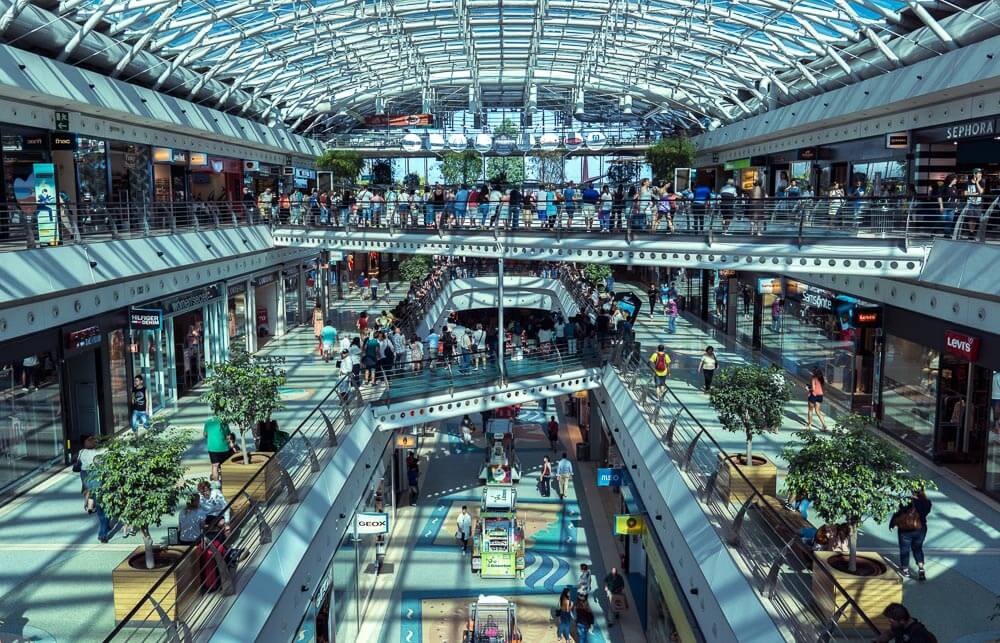Passarelas no interior do Centro Comercial Vasco da Gama, em Lisboa. Há várias pessoas no local de arquitetura moderna e teto de vidro.