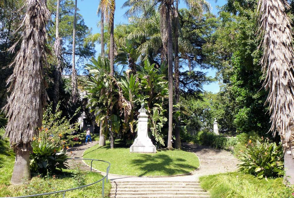 Escadaria com estátua rodeada de árvores no Jardim Botânico, em Lisboa.
