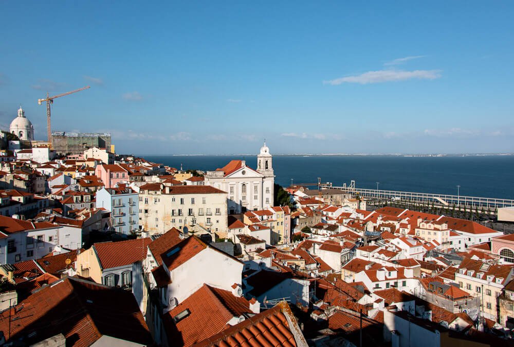 Vista do Miradouro de Santa Luzia com casas do bairro de Alfama e o rio Tejo ao fundo.