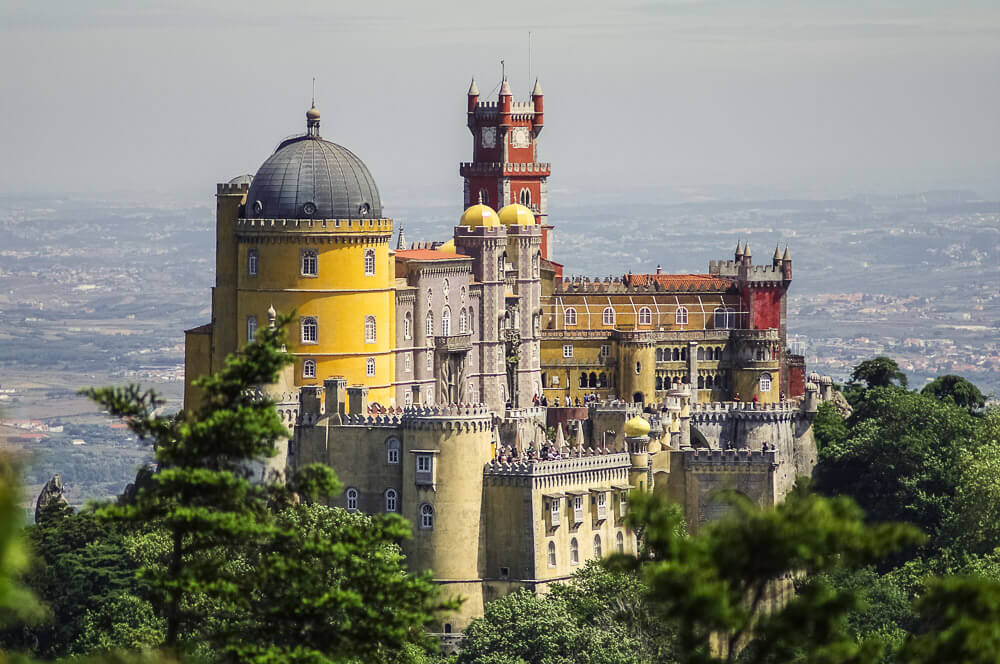 Palácio da Pena com estrutura imponente, em um ponto alto da cidade de Lisboa.
