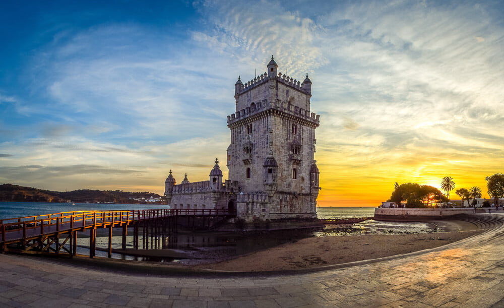 Torre de Belém em um pôr do sol à beira do Rio Tejo.