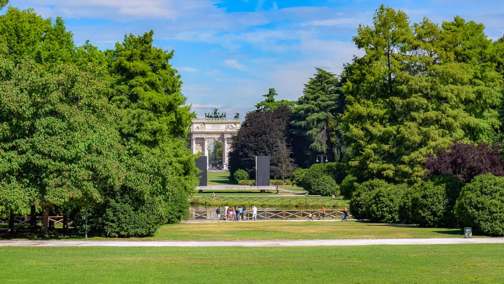 Parque Sempione em um dia de sol. Ao fundo, o Arco della Pace.