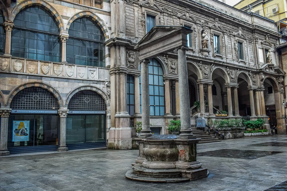 Praça dei Mercanti com prédios de arquitetura medieval em volta.