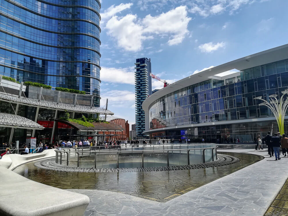 Praça Gae Aulenti com arquitetura moderna e prédios luxuosos ao fundo.