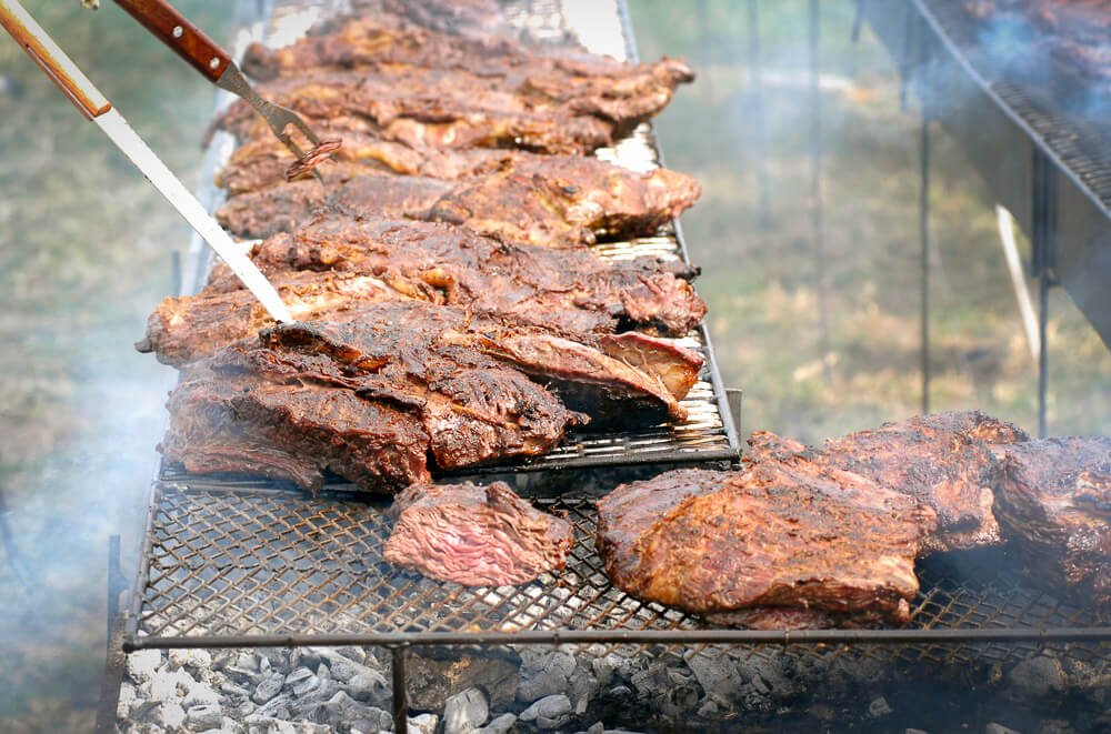 Churrasco típico de Montevidéu. Há muitas carnes sobre uma churrasqueira.