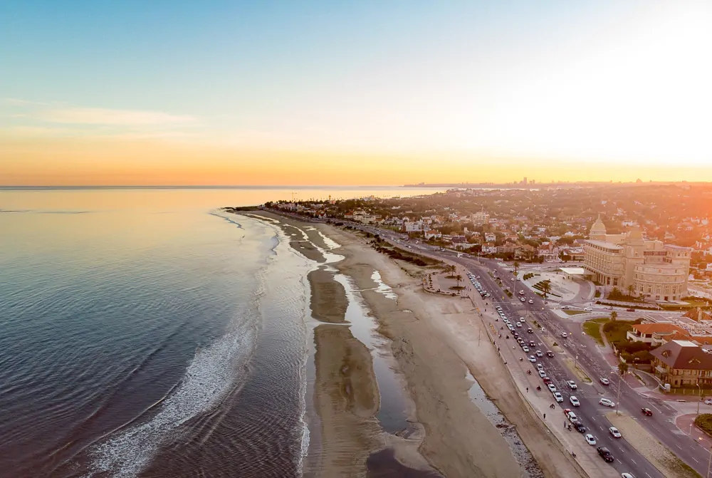 Vista panorâmica para a Praia de Carrasco em um fim de tarde. Há uma avenida à beira-mar.