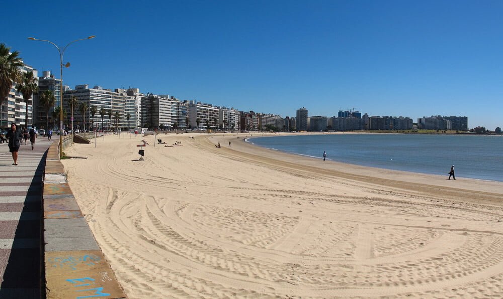 Praia de Pocitos com grande faia de areia e prédios em frente ao mar.