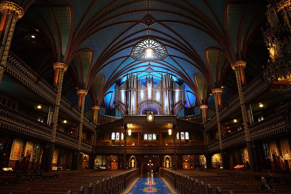 Visão interior da Basílica de Notre Dame. Há muitos bancos de igreja e um teto curvado.