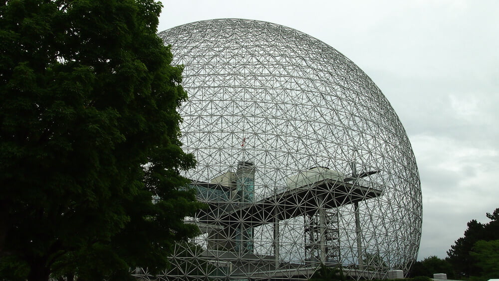 Biosfera de Montreal vista por fora. Há árvores ao redor da grande esfera metalizada.
