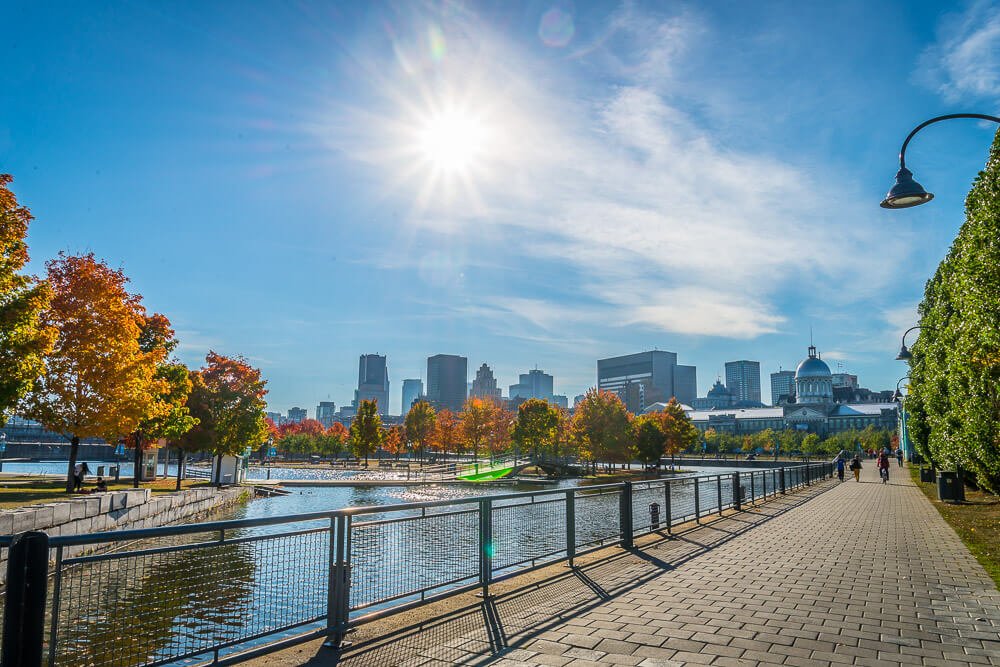 Velho Porto de Montreal em um dia de sol. Há uma grande calçada na região costeira.