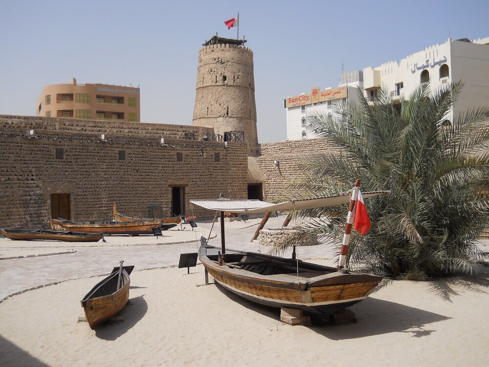 Museu de Dubai com fachada de pedras e pequena faixa de areia em frente.