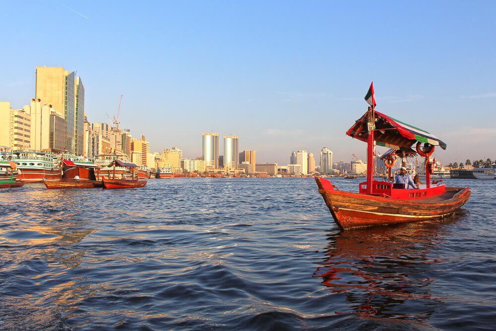 Rio Dubai Creek com barcos de passeio e prédios ao fundo.
