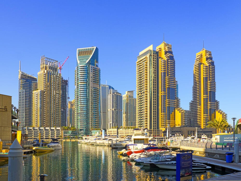 Arranha-céus na região da Marina de Dubai. Há barcos nas águas cristalinas do local.