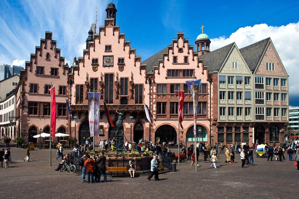Prédios na Cidade Velha de Frankfurt com arquitetura enxaimel e pessoas circulando.