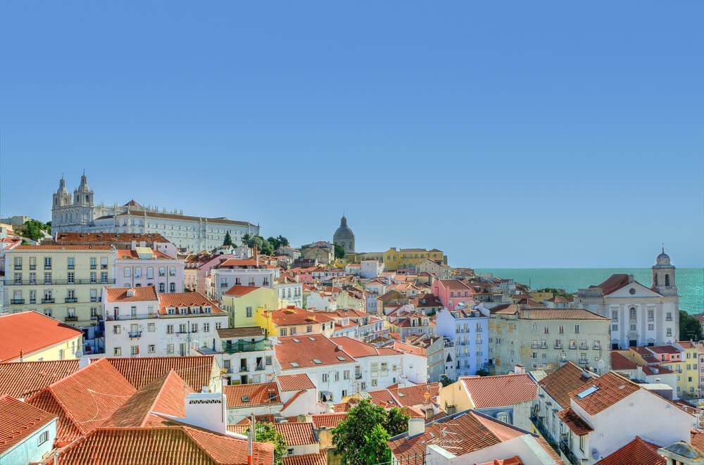 Vista panorâmica da cidade de Lisboa, em Portugal. Há vários prédios e casarões coloridos.