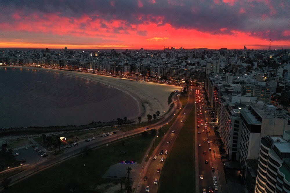 Vista aérea e noturna da região de Pocitos. À esquerda, está o mar e à direita prédios de luxo.