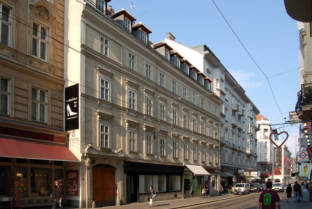 Rua na região de Josefstadt com edifícios cheios de janelas na horizontal e pintados com cores claras.