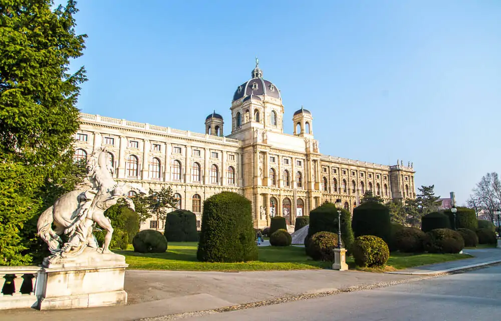 Jardim do Museu de História Natural com fachada majestosa e cúpula cinza.