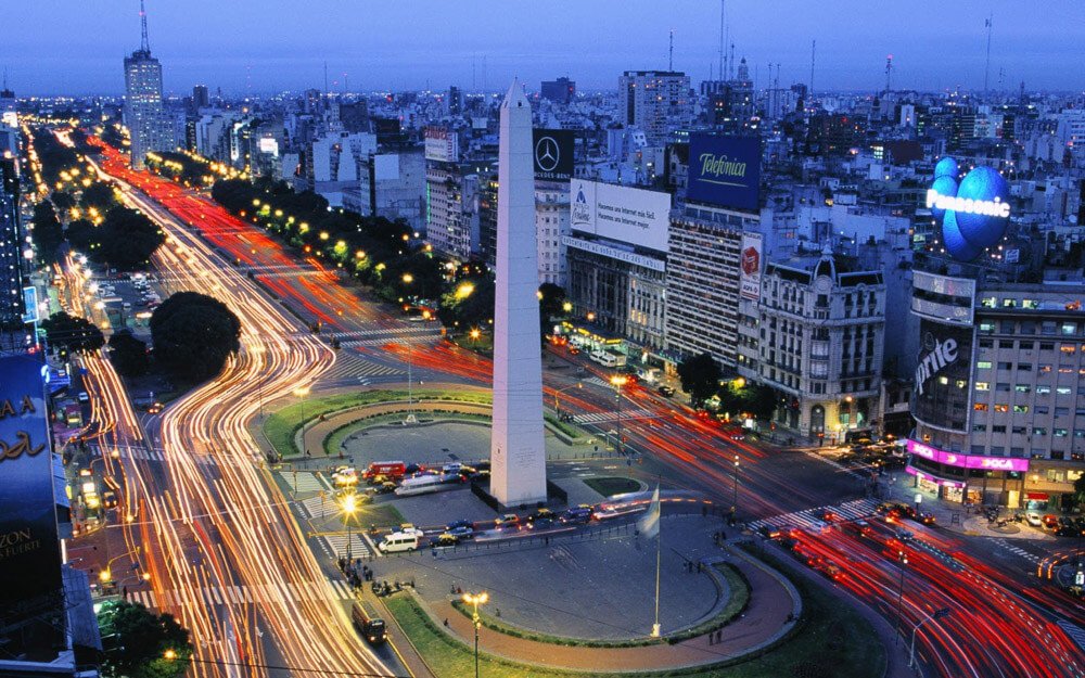 Visão superior do Obelisco de Buenos Aires, iluminado pelas luzes dos carros nas vias laterais.