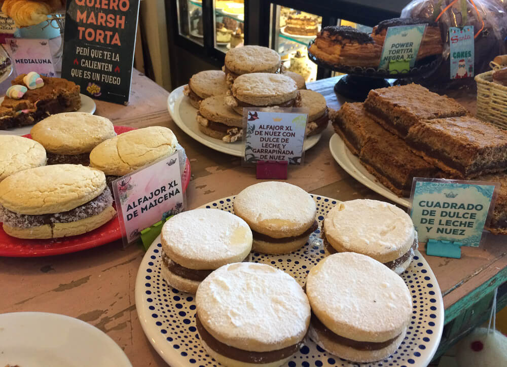 Mesa com vários pratos com vários doces e alfajores.