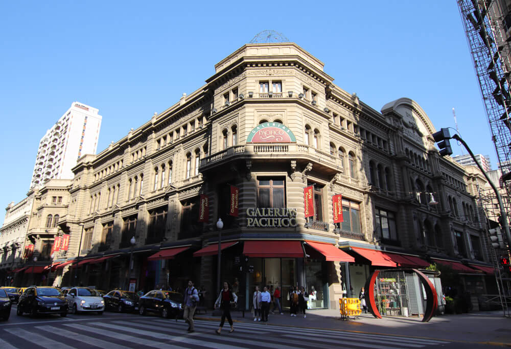 Galerías Pacífico e rua ao lado com automóveis e pessoas transitando pelo local.