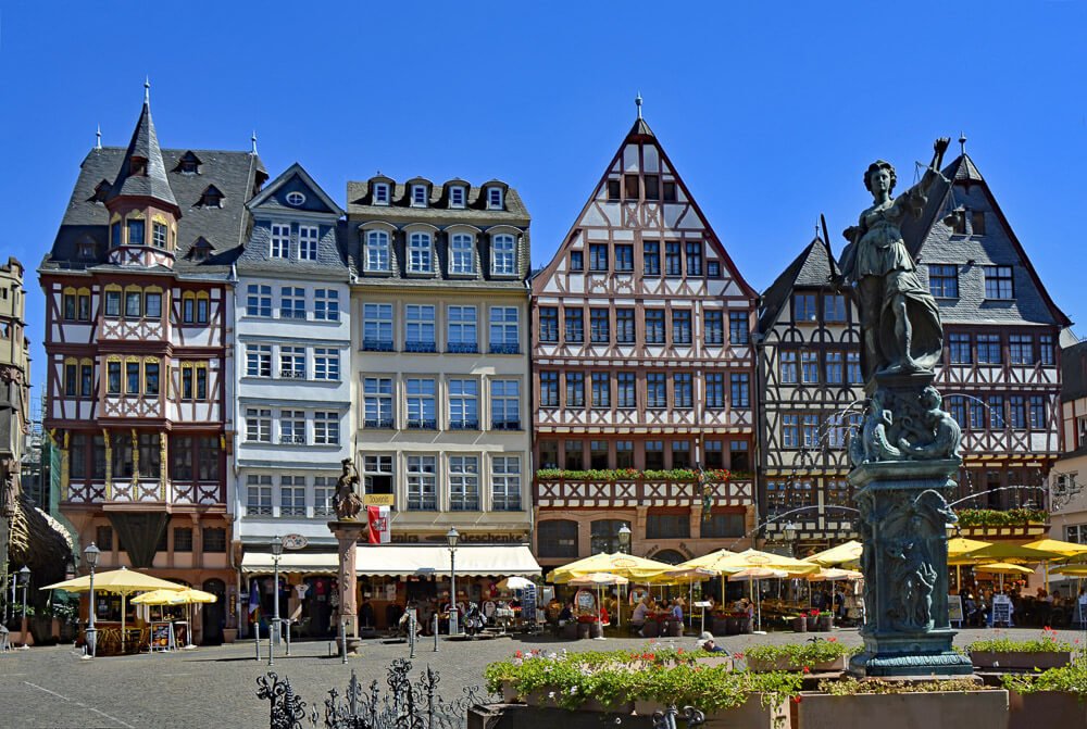 Praça Römerberg com várias casas tradicionais de Frankfurt, restaurantes e uma estátua.