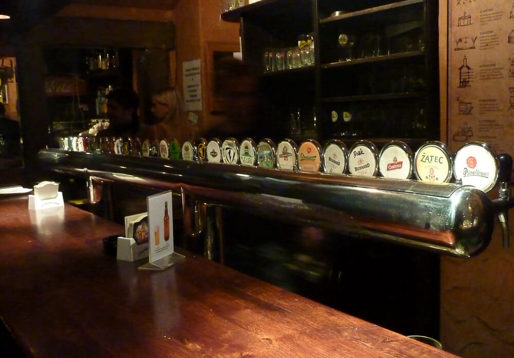 Balcão interior do Czech Beer Museum e um armário cheio de copos de vidro, em Praga.