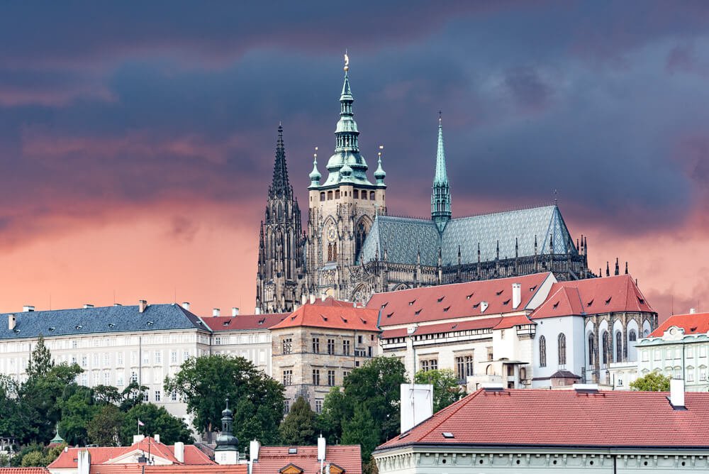 Castelo de Praga com vários edifícios e árvores nos arredores.