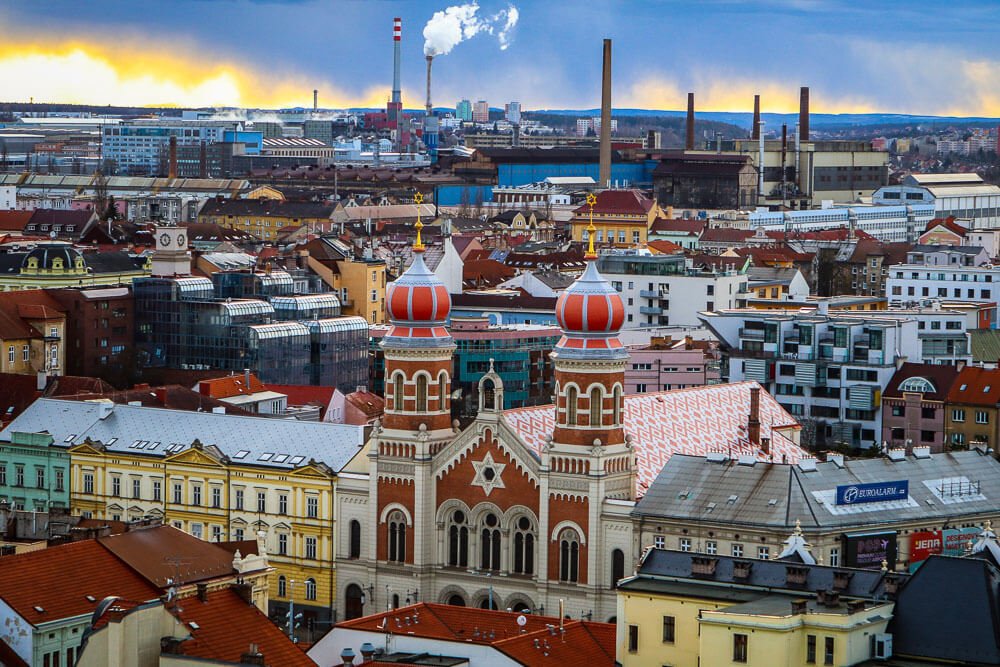 Panorama da cidade de Pilsen com prédios coloridos e uma área industrial.