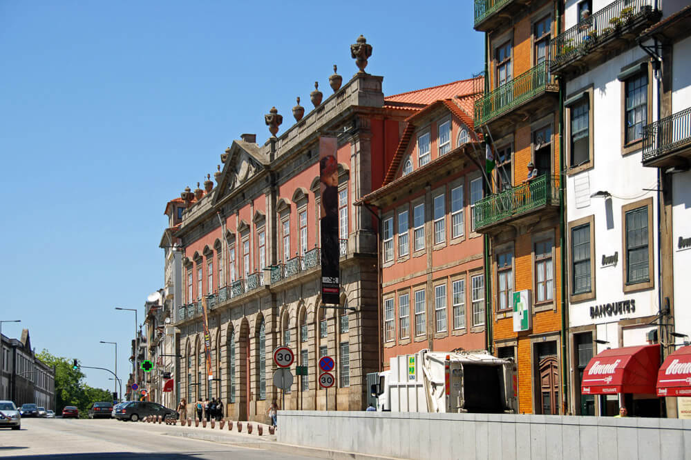 Rua com edifícios coloridos e com o Museu Nacional Soares dos Reis, na região de Miragaia.
