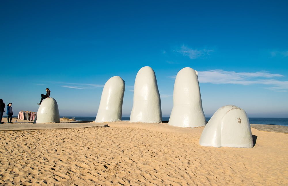 Escultura La Mano e alguns turistas aproveitando a atração, na Playa Brava.