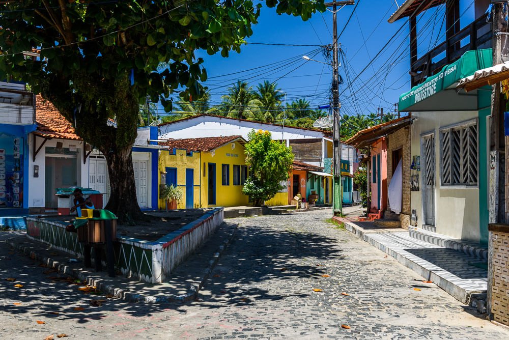 Cruzamento de ruas em Velha Boipeba, com casinhas simples e coloridas.