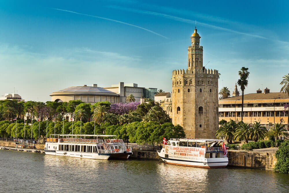 Rio Guadalquivir com dois barcos ancorados em frente à Torre del Oro.