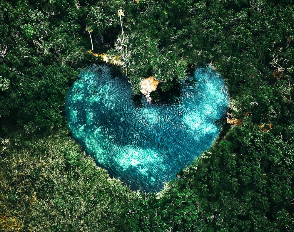 Cenote Corazón visto de cima, com piscina natural em formato de coração e muita vegetação nas laterais.