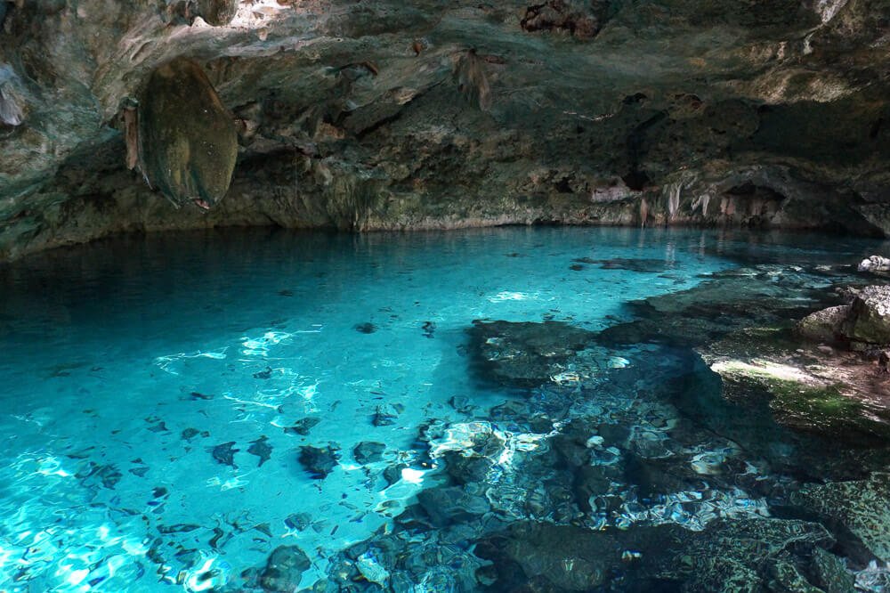 Cenote dos Ojos com águas azuis-turquesa e uma formação rochosa ao redor.
