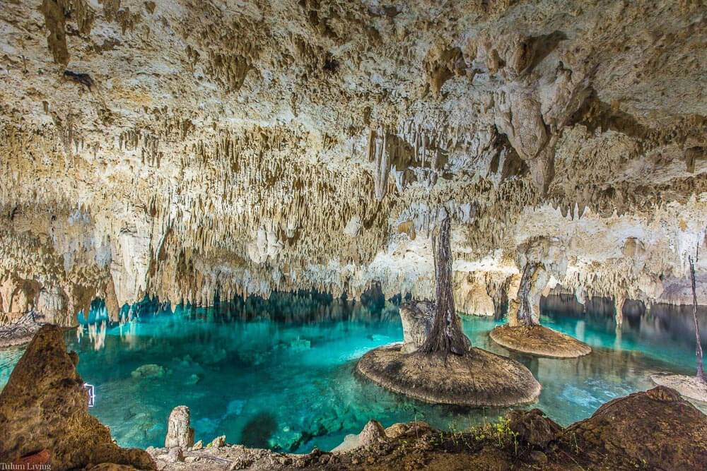 Interior do Cenote Sac Actun, em Tulum, com águas cristalinas e muitas rochas brancas.