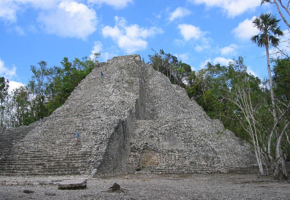 Pirâmide de Nohoch Mul, com estrutura de pedras cinzas e árvores ao fundo, em Cobá.