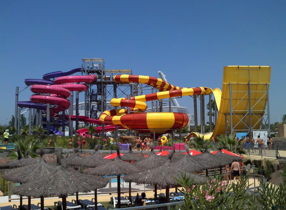 Parque aquático Isla Mágica com vários tobogãs coloridos e toldos de palha.