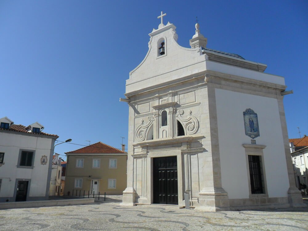 Capela de São Gonçalinho vista de lado, com paredes claras e portas quadradas.